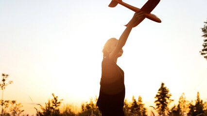 Silhouette of playful preteen girl kid run with airplane on background amazing summer warm sunset. Dream freedom concept. Child runs on field holding in hands toy aircraft