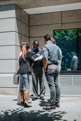 A group of business coworkers discussing work outside, highlighting teamwork and collaboration.