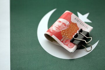 Pakistan rupees banknotes on Pakistani flag. The current Pakistan money bills