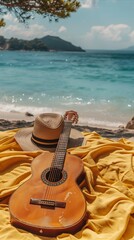 An acoustic guitar and straw hat resting on a yellow blanket on a sun-drenched beach with blue ocean in the background. Summer vacation leisure concept.