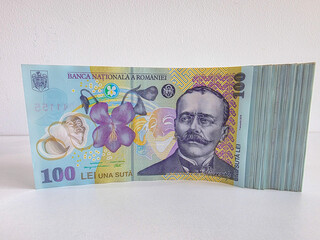 Stack of Romanian Lei bank notes, 100 RON denomination on their side against a white background 