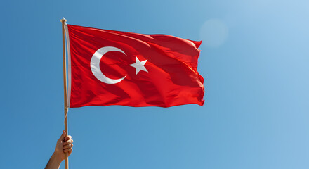 Hand holding a red national flag turkery waving in a clear blue sky