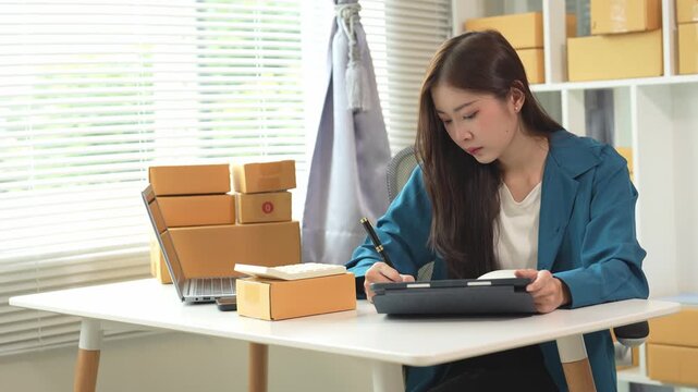 Asian business woman Small Business Entrepreneur, SME Business at Home with Internet Online Young woman feels happy and enjoys checking orders in online business