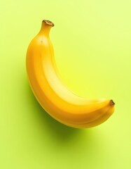 Single ripe banana on pastel green background, vibrant yellow hue, healthy, fruit