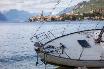 A grounded sailboat lies in the foreground, tilted slightly on the pebbled shore—its white hull...