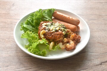steamed macaroni dressing fried chop pork and slice tomato in ketchup sauce with sausage couple lettuce on plate  