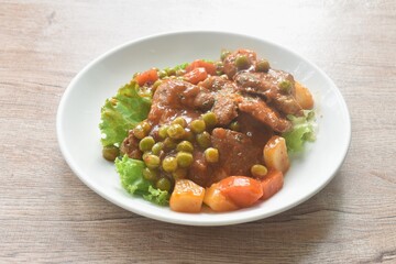 braised pork steak in gravy sauce stew with vegetable topping fresh lettuce on plate
