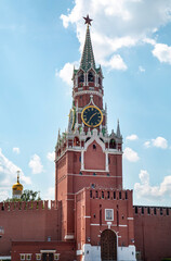 The Spasskaya Tower of the Kremlin against the background of white clouds on a clear sunny day, Moscow.  Sights of Russia. Architecture of World tourism.