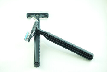 Two black disposable razors, one upright and one lying across the other, on a white background.