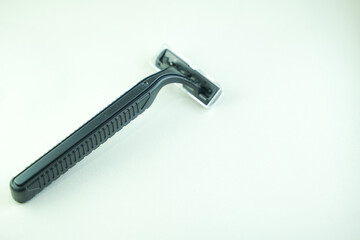 A black razor lies on a white surface, providing a clean, close-up view.