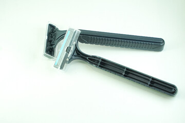 Two black disposable razors lie on a white background, showcasing their design and functionality.