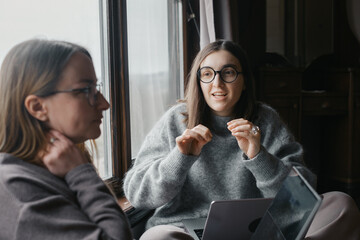 Two young women are collaborating on startup. Working with laptops, having discussion. Female business, working remotely, listen attentively Strategic planning, cooperation, and brainstorming concepts