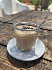 Cold coffee mousse in glass cup on rustic wooden table