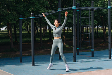 young slim caucasian woman doing jumping jack exercises outdoors in summer, street sports ground,...