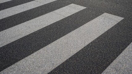 Fototapeta premium Urban crosswalk closeup with asphalt texture and white stripes, city zebra crossing for pedestrian safety and street transportation concepts