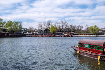 Fototapeta premium Beijing, China. Wooden tour boats docked at the lake in Shichahai, traditional Chinese architecture buildings, blue sky.