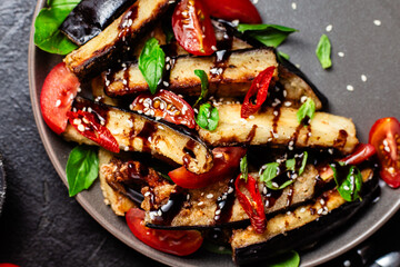 Appetizing salad of eggplants, tomatoes and basil in a black plate