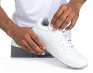 A person is holding a white sneaker, showcasing its design and detailing, emphasizing style and footwear functionality.