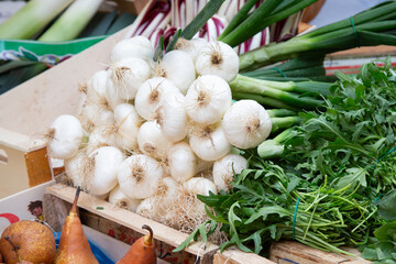 A large wooden box filled with vegetables like onions and pears