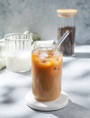Ice latte coffee in a glass with milk on a marble stand on a light background with coffee beans