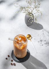 Ice latte coffee in a glass with milk on a white background with bouquet of flowers