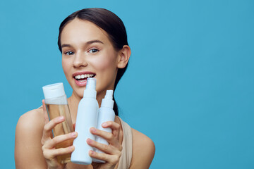 Young female model showcasing hair care products against a blue background, smiling happily,...