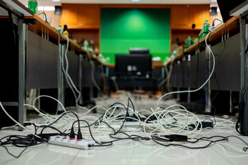 Messy network and power cables tangled on the floor in a meeting room, representing poor cable management, office hazards, or IT infrastructure setup challenges.
