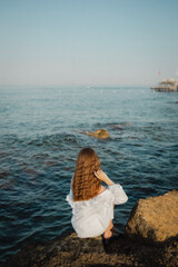 beautiful young girl with a beautiful athletic figure of European appearance in a swimsuit and underwear on the ocean shore in the open air. Sea waves and rocks with blue water. Travel and recreation