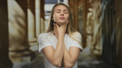Woman holding neck in pain on a historic city street with classic architecture background indicating discomfort outdoors during daytime.