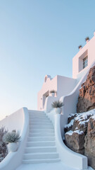 Stunning white building with curved staircase leads up to serene sky, surrounded by rocky terrain and minimalistic plants, creating tranquil