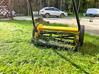 Lawn mower cutting grass in a well-maintained yard on a sunny day