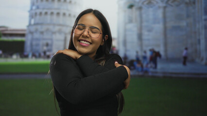 Woman crossing arms while hugging in front of pisa shows young latin hispanic style by historic...