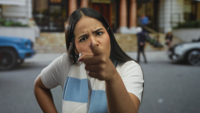 Woman extends finger while pointing down a street as young latin hispanic angry speaker looks into camera outdoors. - Powered by Adobe