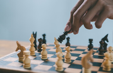 male hand moving chess piece on chess board game, business success, business competition planning teamwork strategic concept.