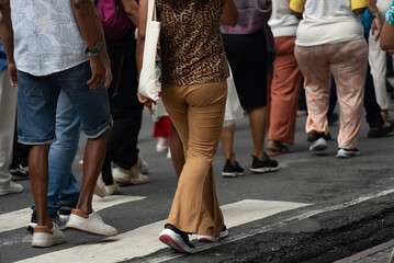 Lower body view of unidentified people walking on a paved street on a hot, sunny day. People in a...