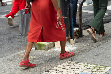 Lower body view of unidentified people walking on a paved street on a hot, sunny day. People in a...