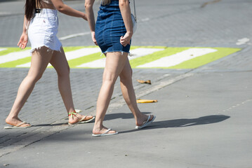 Half-body view of two unidentified people walking down a street from a sidewalk. Pedestrians. Brazil