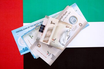United Arab Emirates dirham currency money bills lies on flag. The concept of business and...