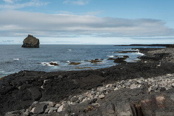 Rocky Coastline with Sea Stack Under Cloudy Sky
