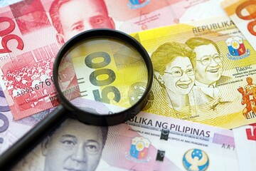 Philippines peso currency money bills and magnifying glass. The concept of financial monitoring and taxation