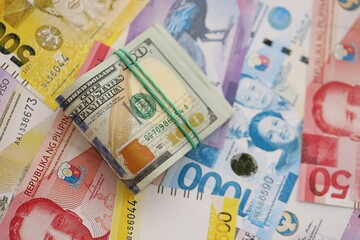 Philippines peso currency money bills and bunch of us dollar banknotes. The concept of economics...