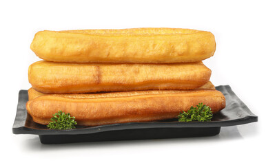 Crispy doughnuts stacked on a black plate with parsley garnish celebrating traditional treats in a clean background