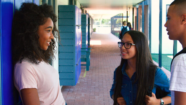 Group Of High School Student Friends Meeting By Lockers Outside College Building