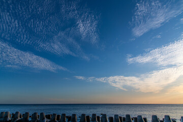tranquil seascape with tetrapods and clouds during sunset