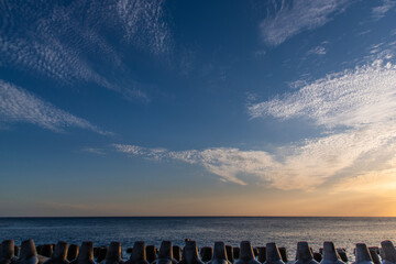 tranquil seascape with tetrapods and clouds during sunset