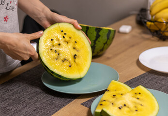 Person cuts watermelon with yellow flesh