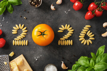 The year 2026 lined with tomatoes and pasta on a dark stone background. A culinary design for the new year.