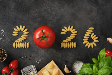 Numbers 2025 made of pasta and red tomato on dark stone background. New year concept.