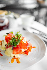 Close-up of a gourmet smoked salmon dish with creamy sauce and fresh greens, beautifully plated on a white surface, highlighting vibrant colors and elegant food styling.
