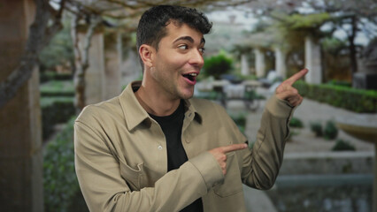 Man lifts hand, showing pointing gesture toward a garden backdrop while young hispanic guy extends...